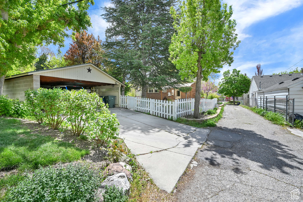 View of side of home featuring a fenced front yard, driveway, and a carport