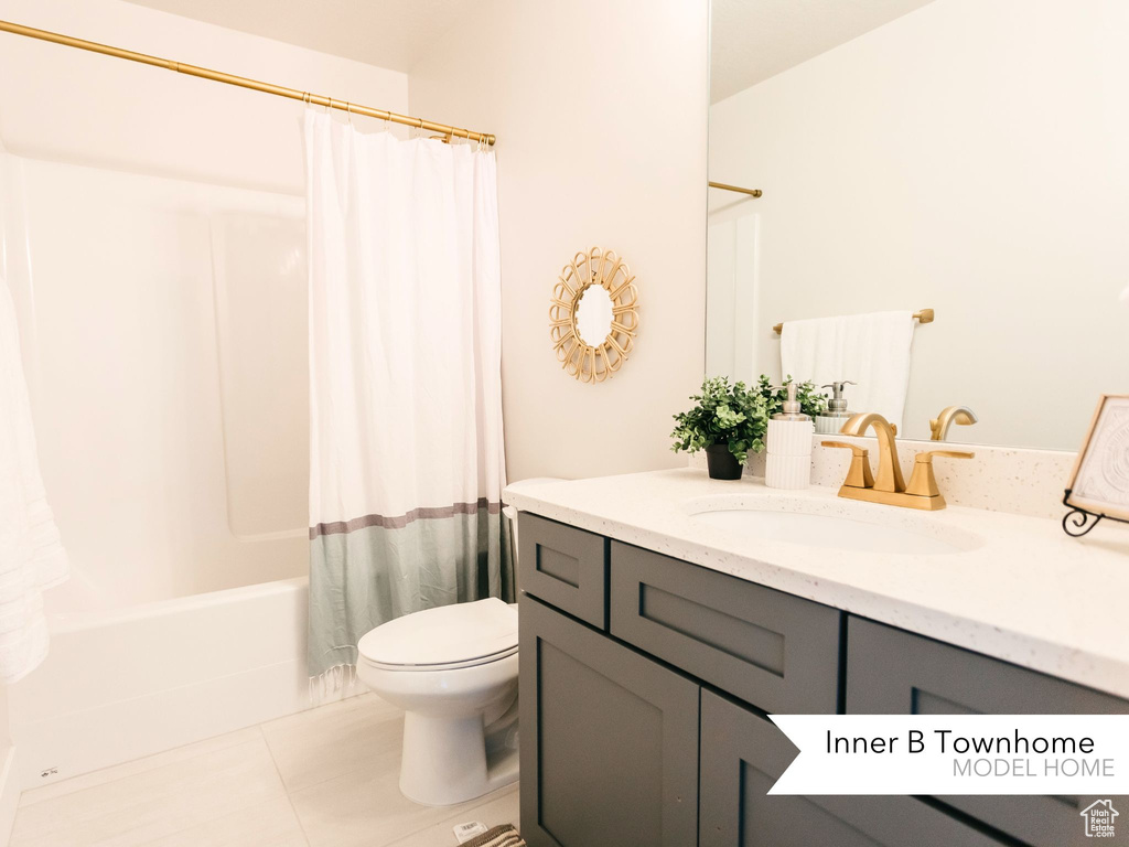 Full bath with toilet, tile patterned floors, shower / bath combo with shower curtain, and vanity