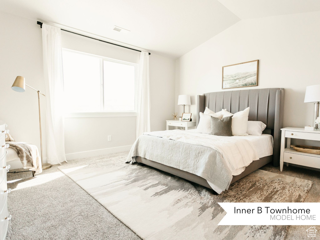 Bedroom with baseboards, visible vents, and lofted ceiling