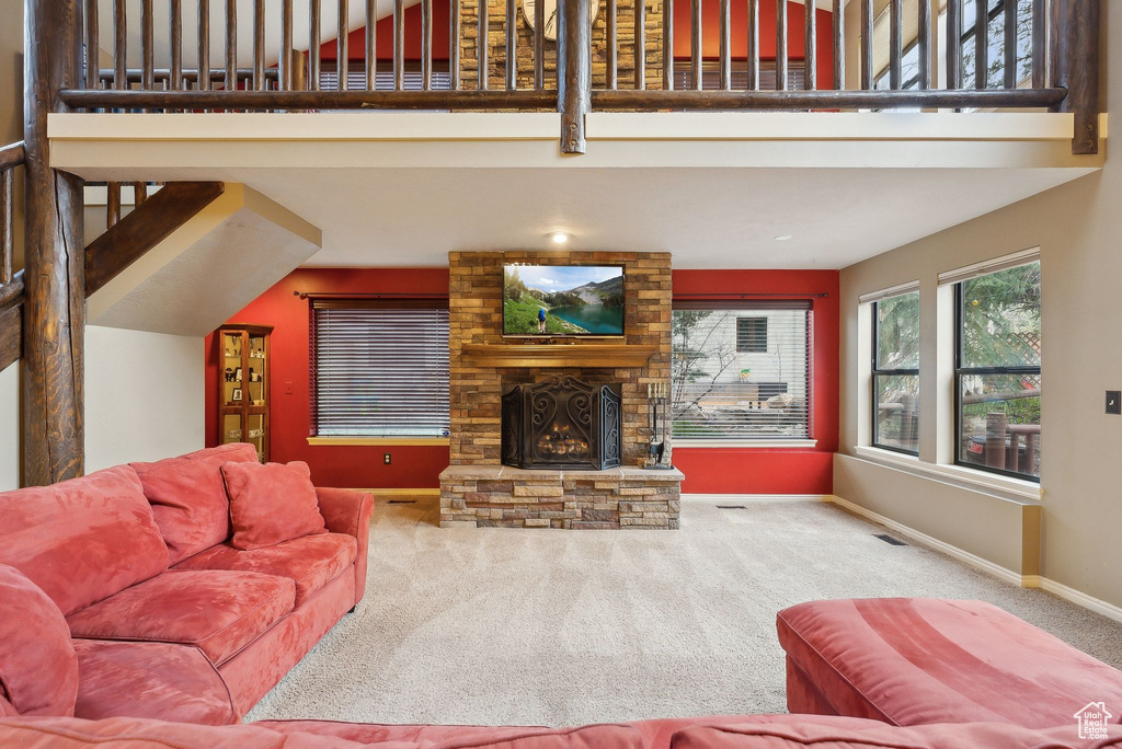 Carpeted living room with a large fireplace, baseboards, visible vents, and a high ceiling