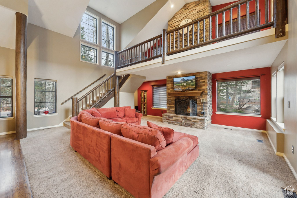 Carpeted living area with a high ceiling, visible vents, baseboards, and stairway