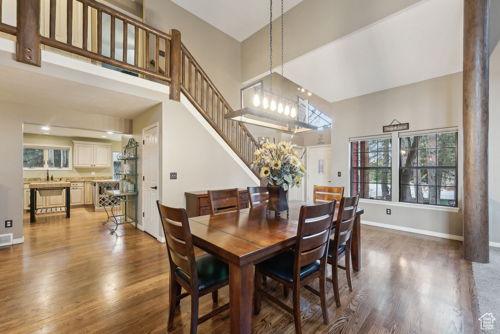Dining room featuring stairs, baseboards, wood finished floors, and a towering ceiling