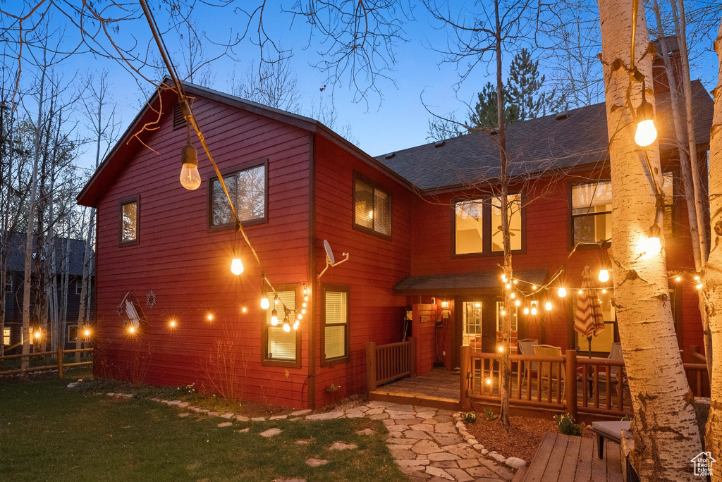 Back of house with a shingled roof, a wooden deck, a yard, and fence