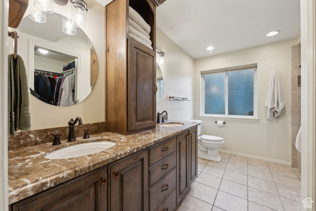 Full bath with double vanity, a sink, tile patterned floors, and toilet