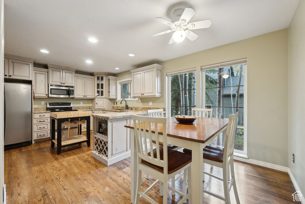 Kitchen with light stone countertops, appliances with stainless steel finishes, a sink, a ceiling fan, and recessed lighting