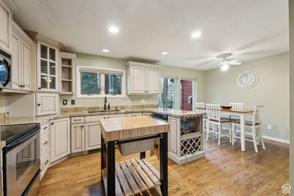 Kitchen with open shelves, a sink, stainless steel appliances, a ceiling fan, and a peninsula
