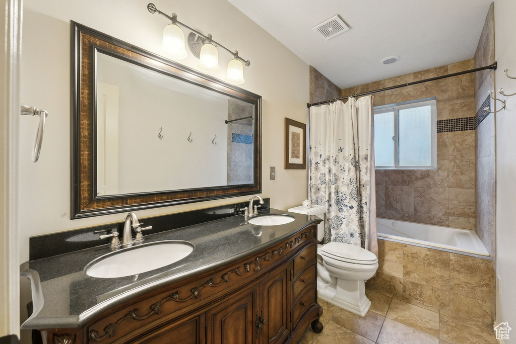 Bathroom with toilet, tiled shower / bath, visible vents, and a sink