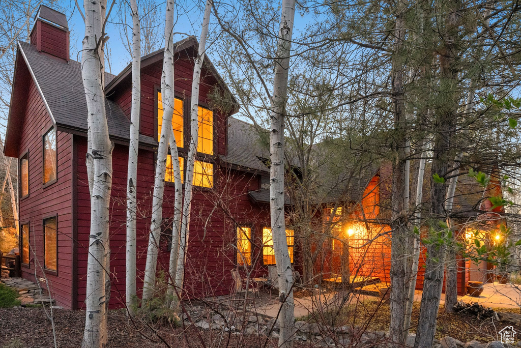 View of side of property with roof with shingles and a chimney