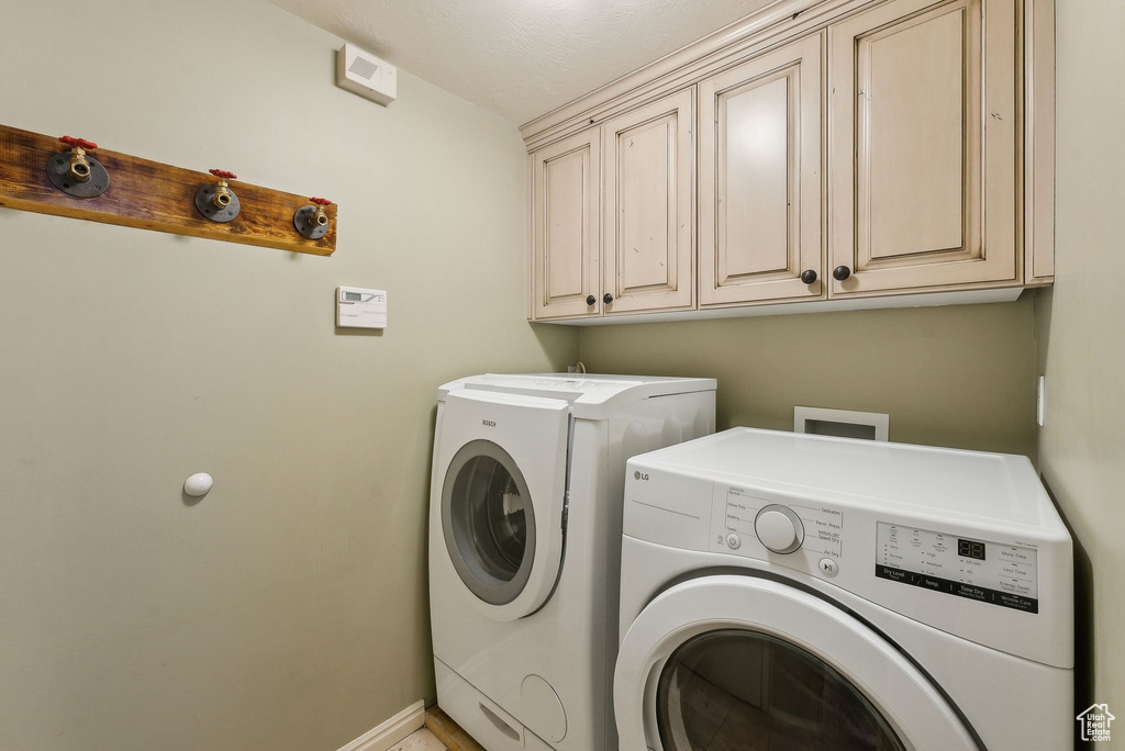 Laundry room featuring separate washer and dryer, cabinet space, and baseboards