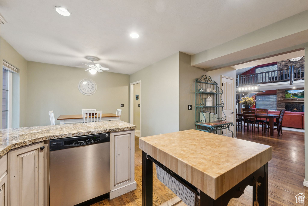 Kitchen featuring a large fireplace, stainless steel dishwasher, a ceiling fan, and light wood-style flooring