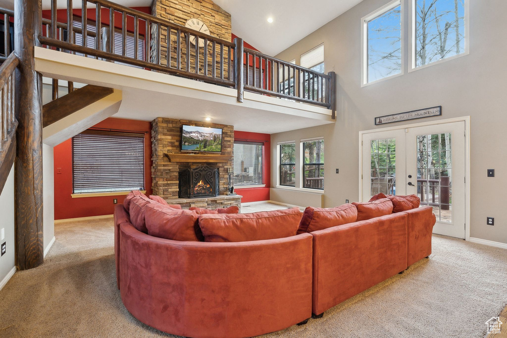 Living room with carpet floors, baseboards, a fireplace, and a towering ceiling