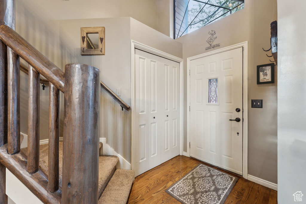 Entrance foyer with baseboards, wood finished floors, stairway, and a towering ceiling