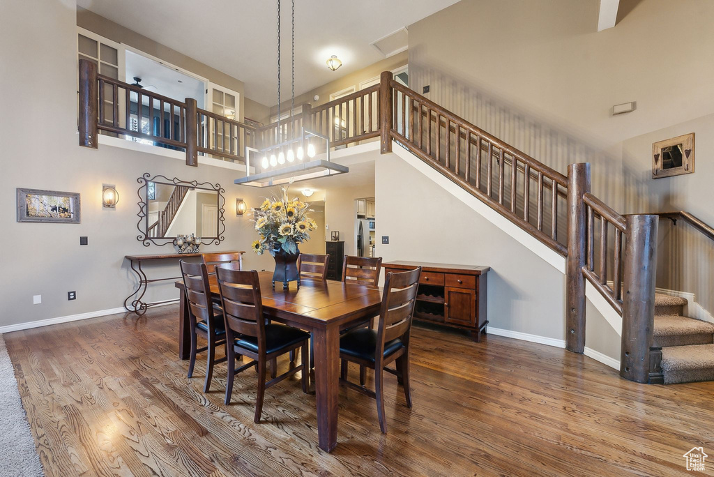 Dining space with stairway, baseboards, wood finished floors, and a towering ceiling
