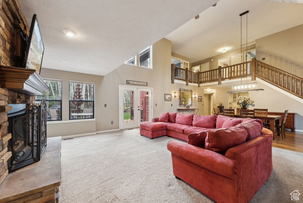Living area with a towering ceiling, a fireplace, stairway, carpet floors, and baseboards