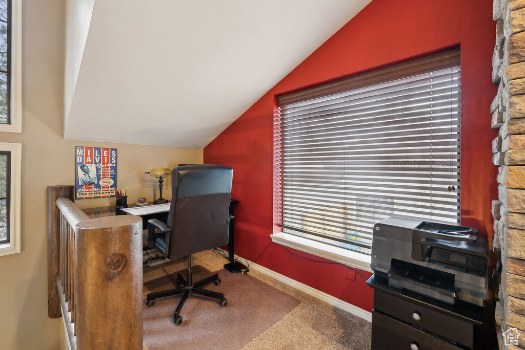 Carpeted office space with baseboards and vaulted ceiling