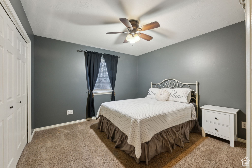 Bedroom with a closet, a ceiling fan, baseboards, and carpet floors
