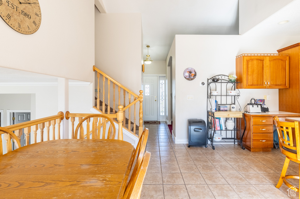 Dining area featuring stairs, crown molding, baseboards, and light tile patterned floors
