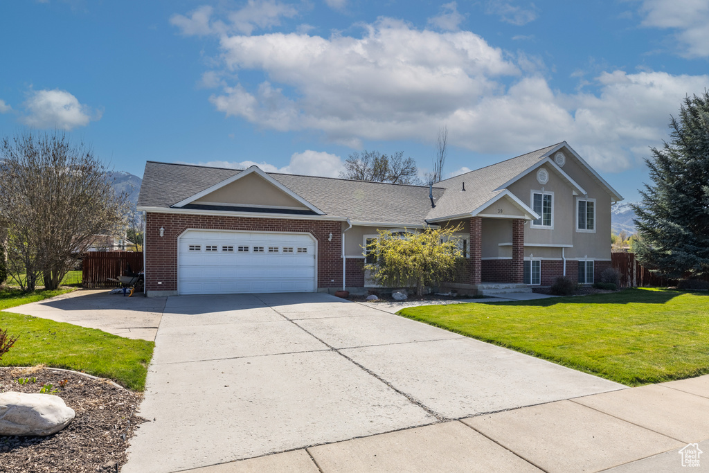 Tri-level home with a garage, fence, a front yard, brick siding, and concrete driveway