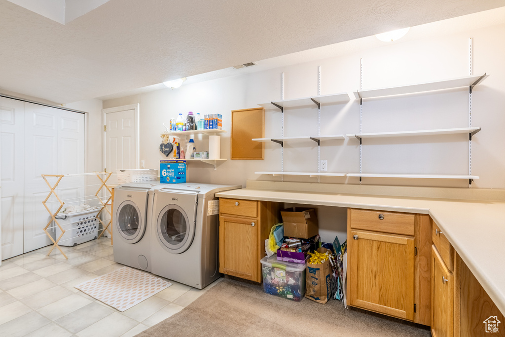 Laundry room featuring separate washer and dryer, cabinet space, light tile patterned flooring, and visible vents