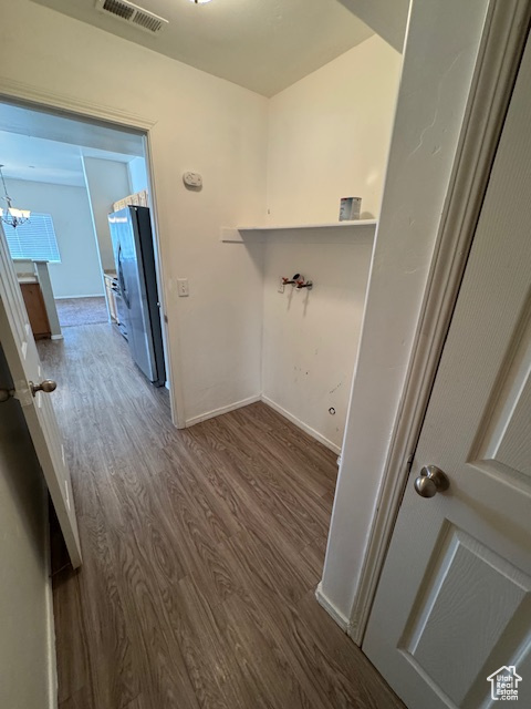 Washroom with visible vents, laundry area, an inviting chandelier, baseboards, and dark wood finished floors