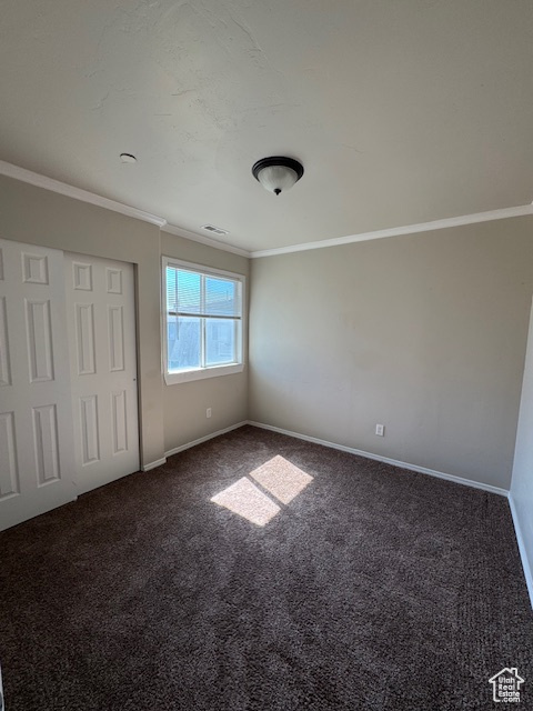Unfurnished bedroom featuring visible vents, ornamental molding, a closet, baseboards, and carpet