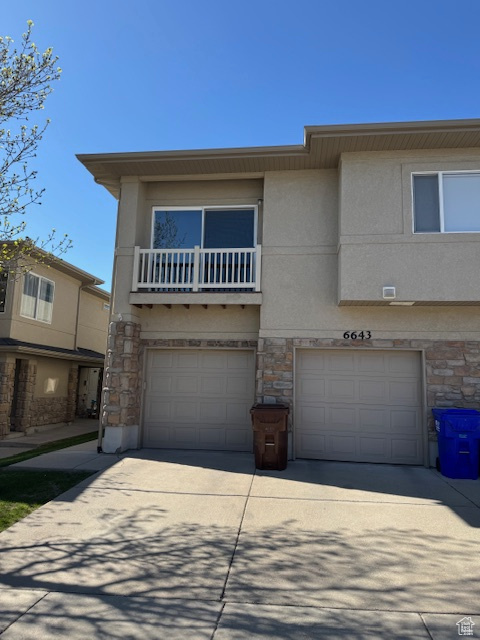 View of front facade with a garage, stucco siding, concrete driveway, and stone siding
