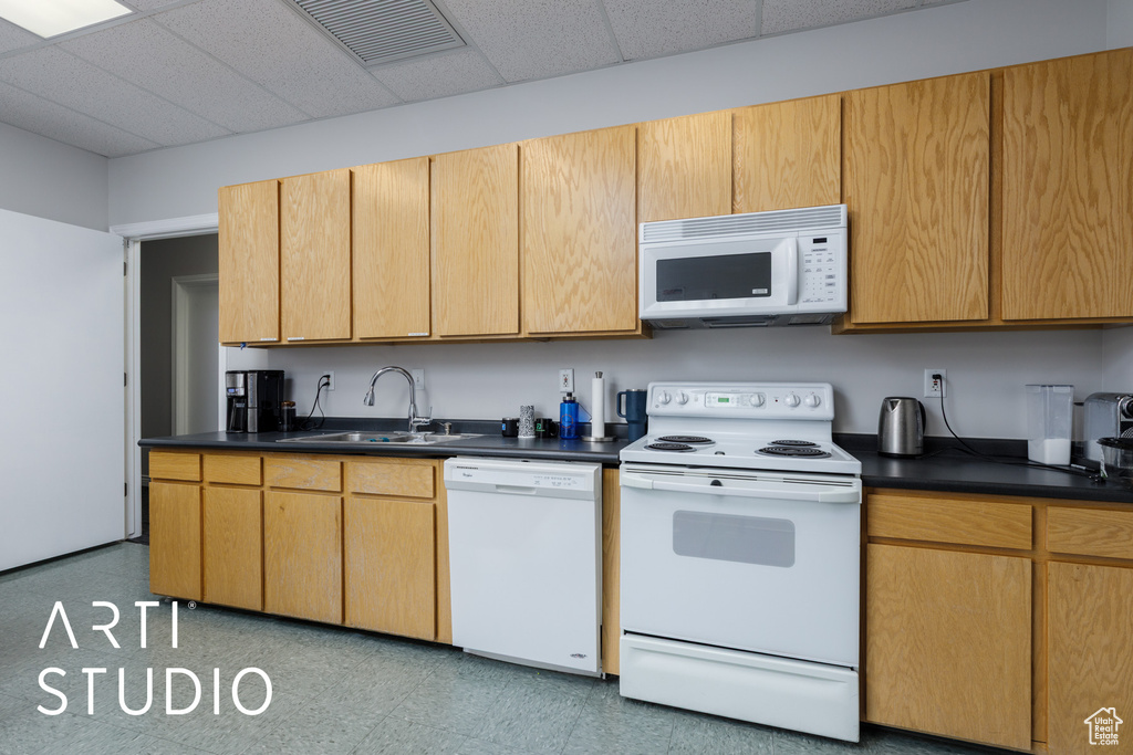 Kitchen featuring visible vents, dark countertops, a sink, light floors, and white appliances