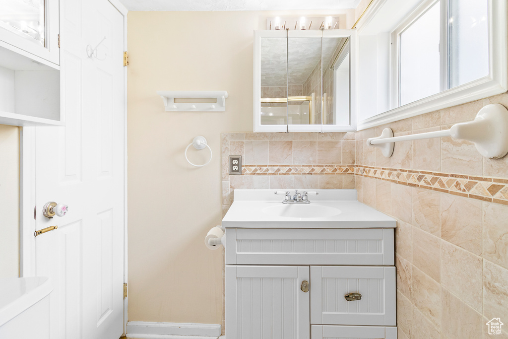 Bathroom with baseboards, walk in shower, tasteful backsplash, and vanity
