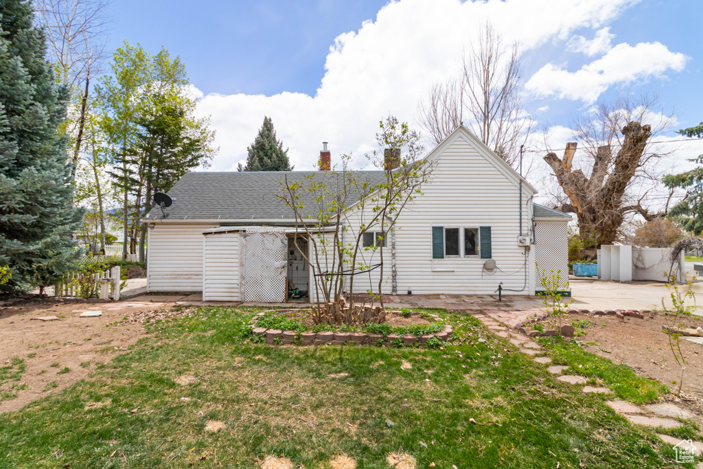 Rear view of property featuring a lawn, fence, a patio, and a chimney