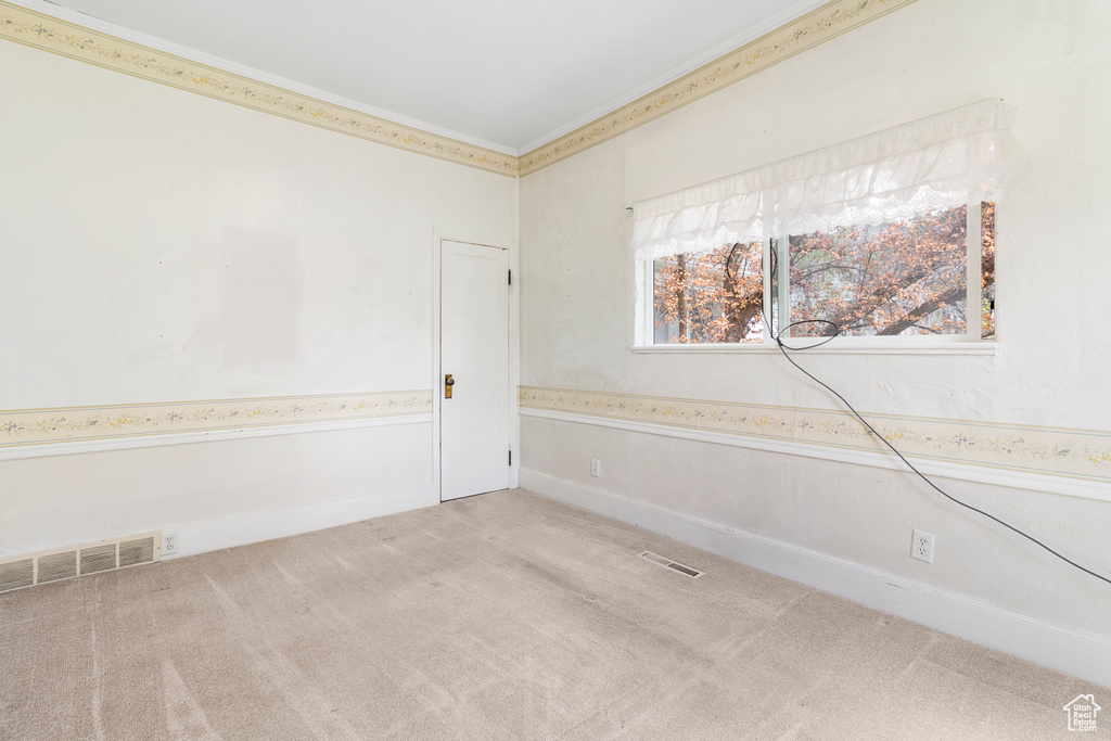 Unfurnished room featuring crown molding, light colored carpet, and visible vents