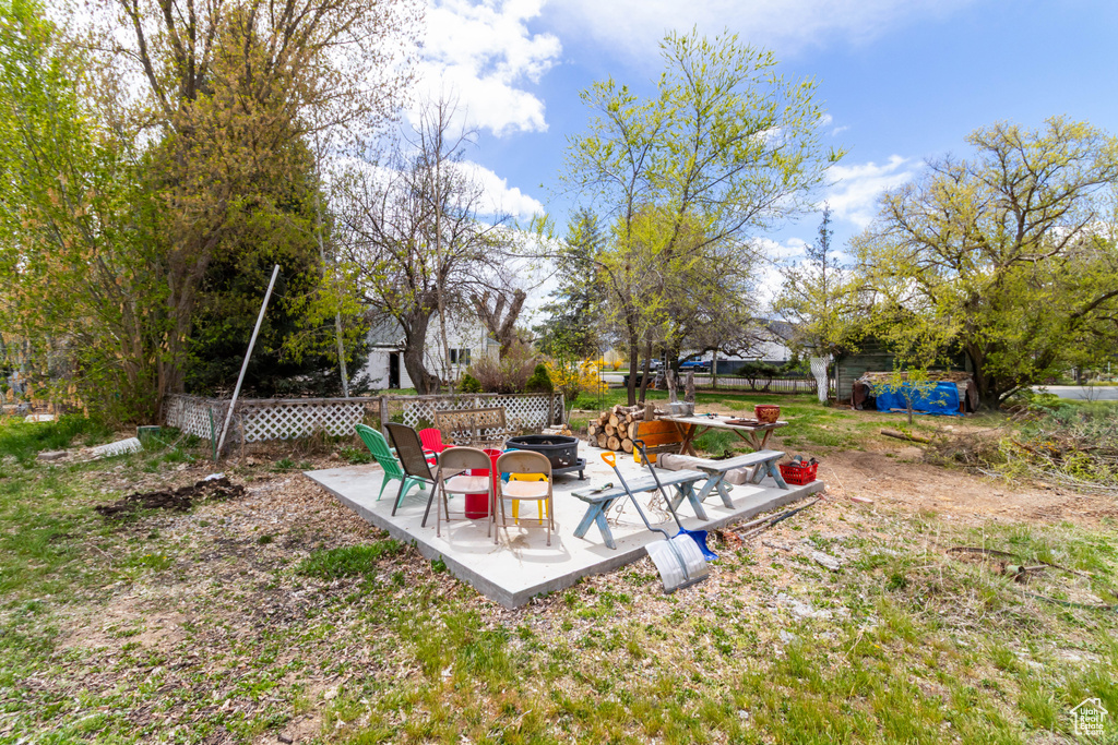 View of yard with fence, a fire pit, and a patio area