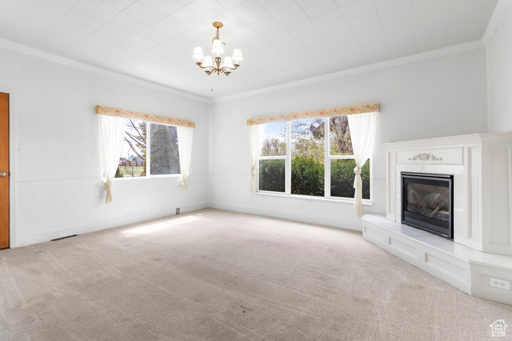 Unfurnished living room with crown molding, a healthy amount of sunlight, and carpet