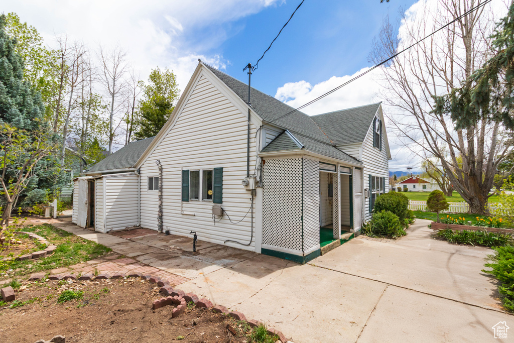 View of home's exterior featuring roof with shingles, a patio area, and fence