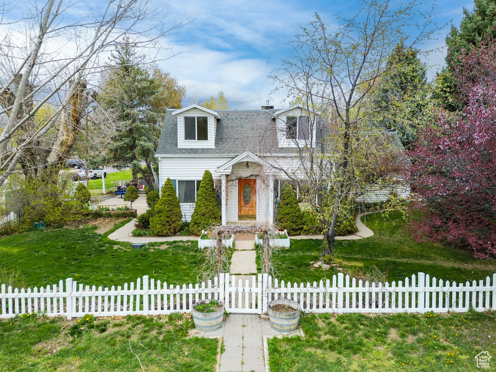 New england style home featuring a shingled roof and a fenced front yard