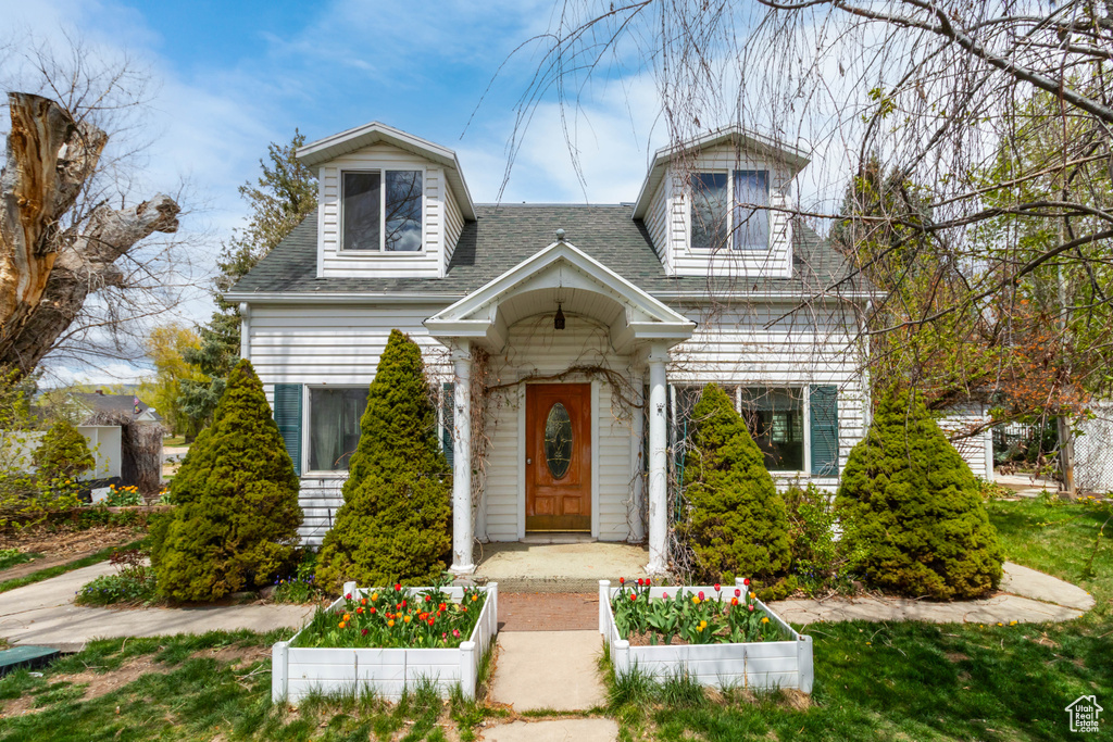 View of front facade with a shingled roof and a vegetable garden