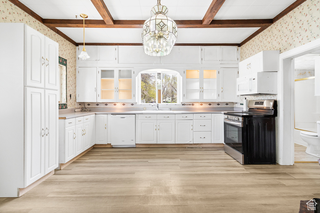 Kitchen with white appliances, wallpapered walls, beam ceiling, and light wood finished floors