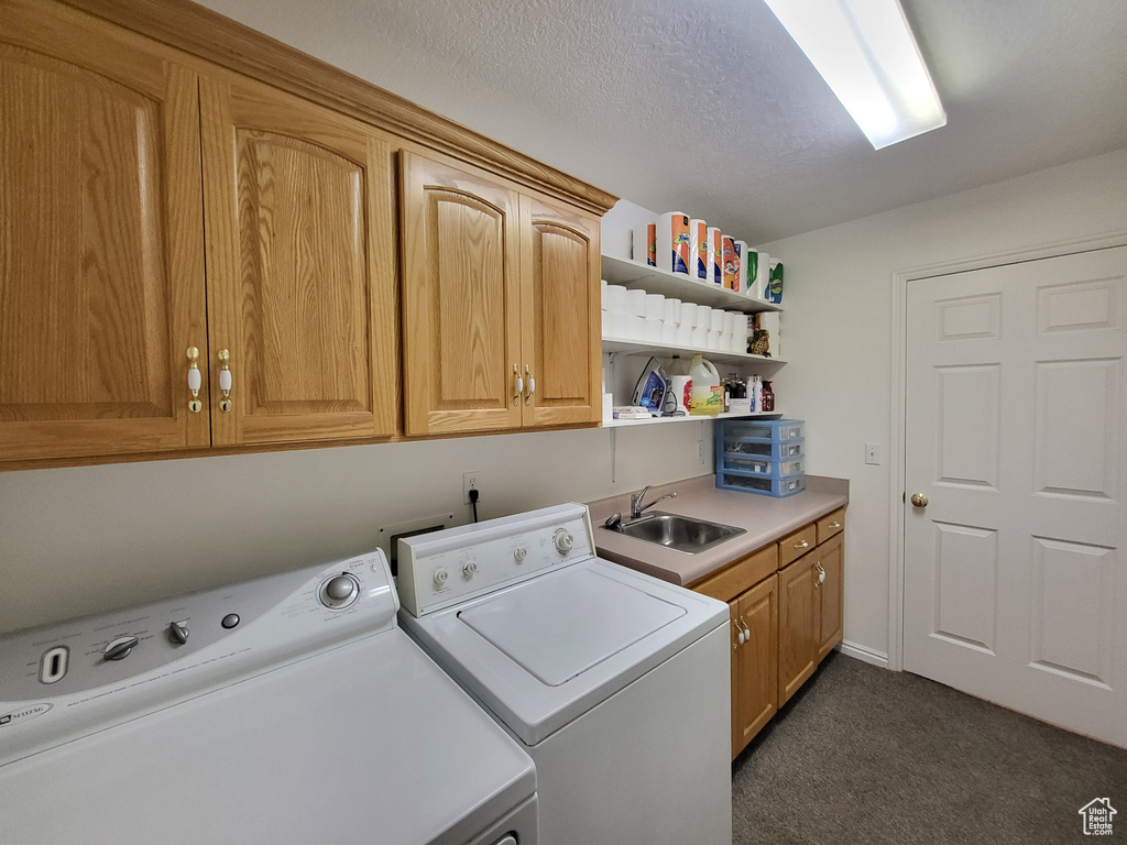 Laundry area featuring dark carpet, a sink, cabinet space, and washer and dryer