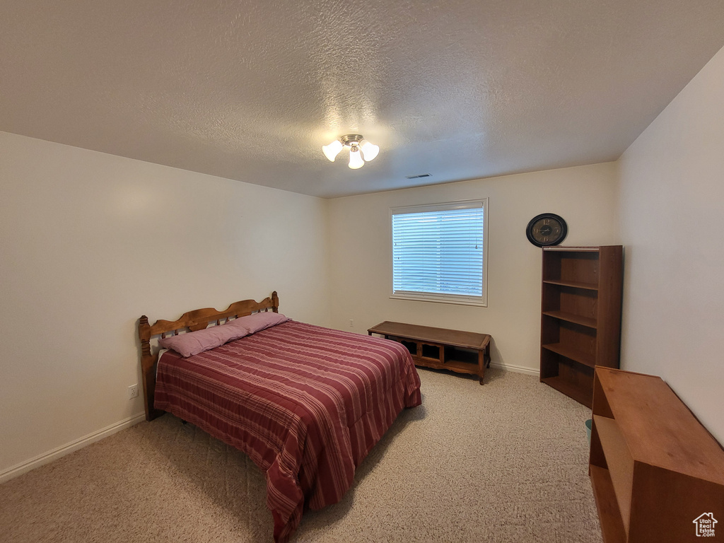 Bedroom with baseboards, a textured ceiling, and light colored carpet