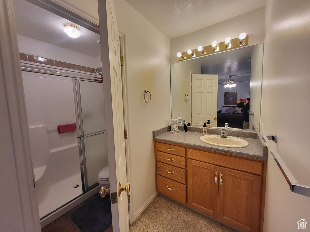 Bathroom featuring vanity, toilet, a stall shower, a ceiling fan, and ensuite bath