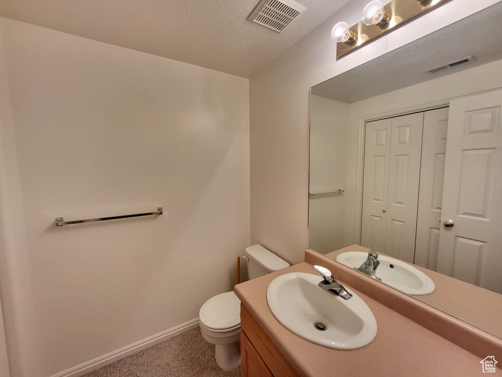Bathroom with toilet, baseboards, visible vents, and vanity