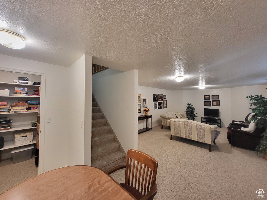 Living area with carpet floors, a textured ceiling, and stairs