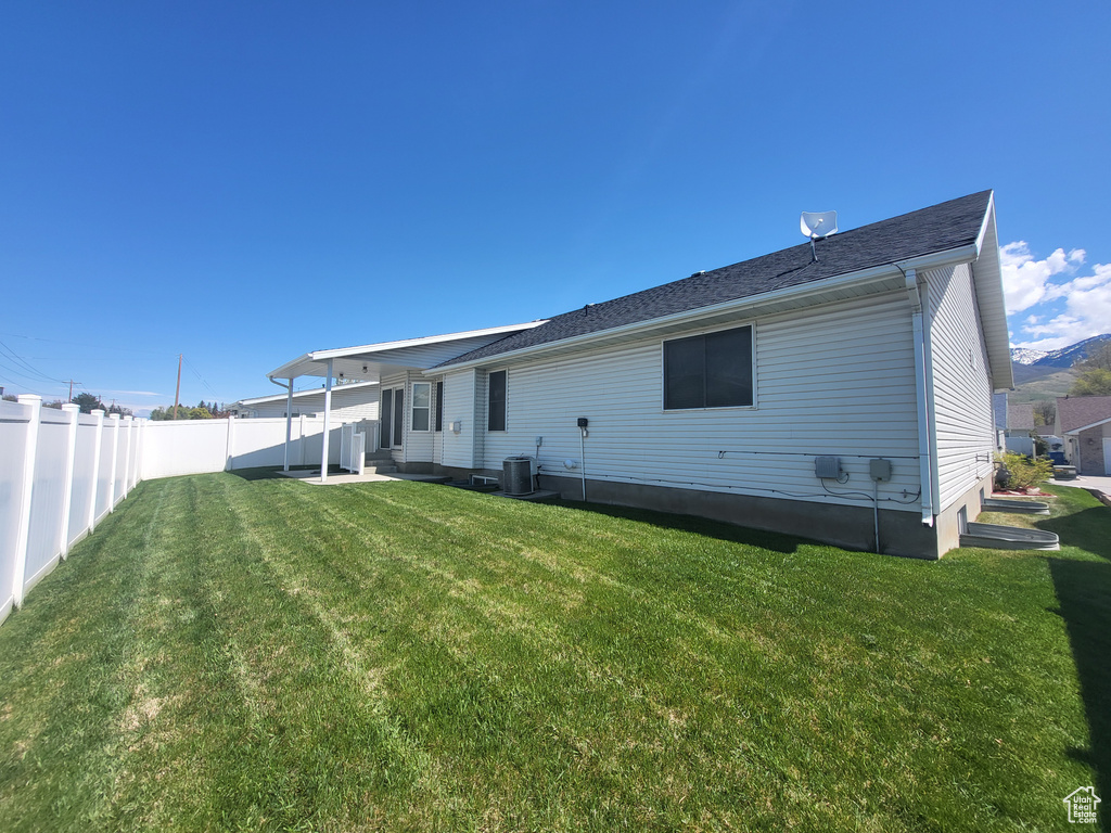 Rear view of property featuring fence private yard, central AC unit, and a yard