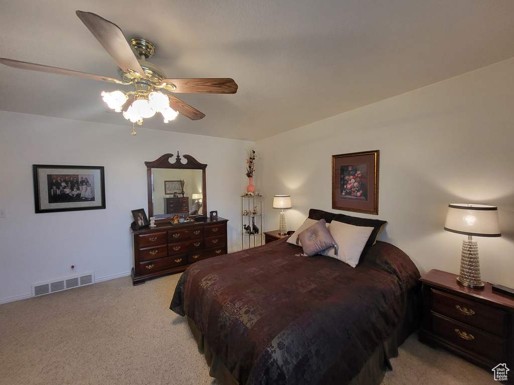 Bedroom featuring light colored carpet, ceiling fan, visible vents, and baseboards