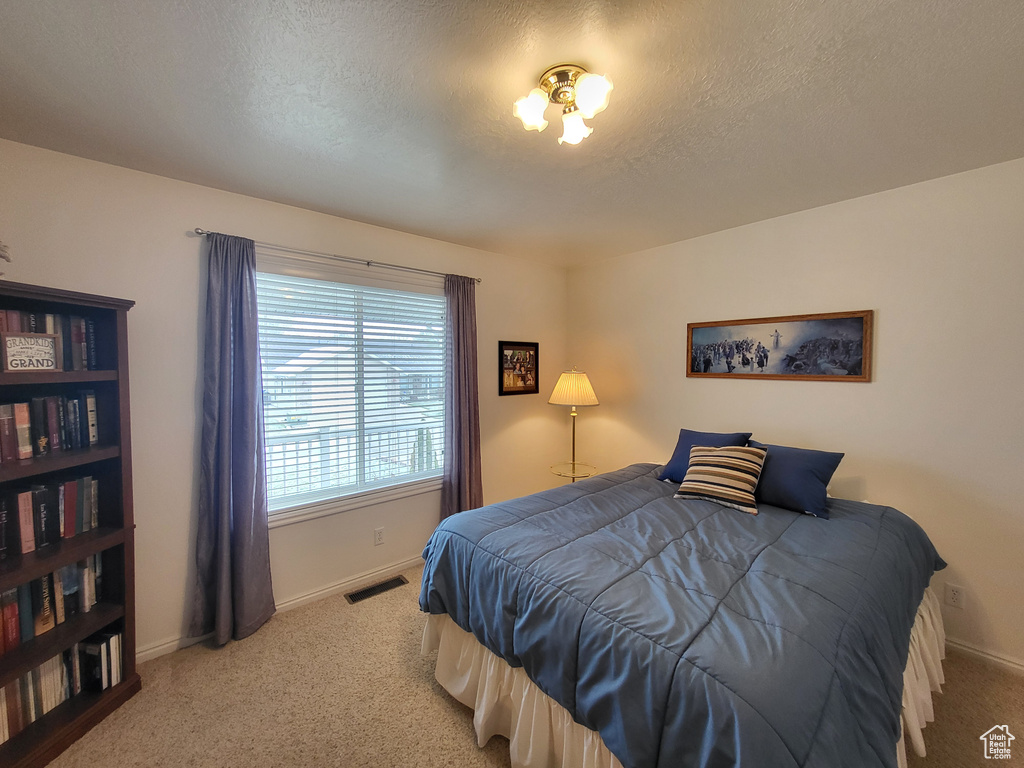 Bedroom with baseboards, carpet, and a textured ceiling