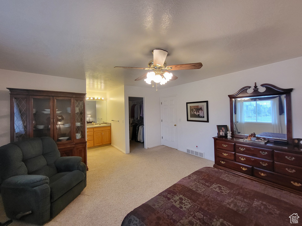 Bedroom featuring visible vents, a closet, light carpet, ensuite bathroom, and a ceiling fan