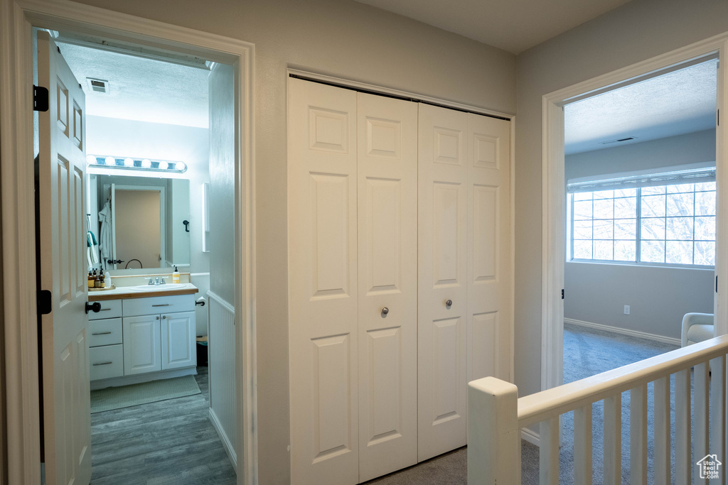 Corridor featuring baseboards, visible vents, a sink, and wood finished floors