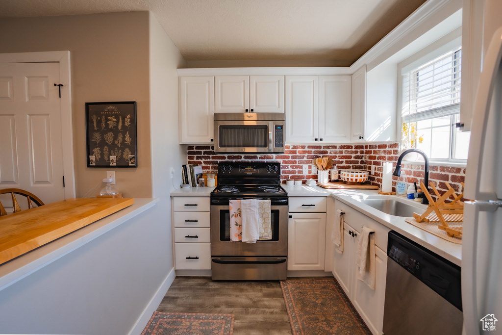 Kitchen featuring light countertops, appliances with stainless steel finishes, a sink, and dark wood-type flooring