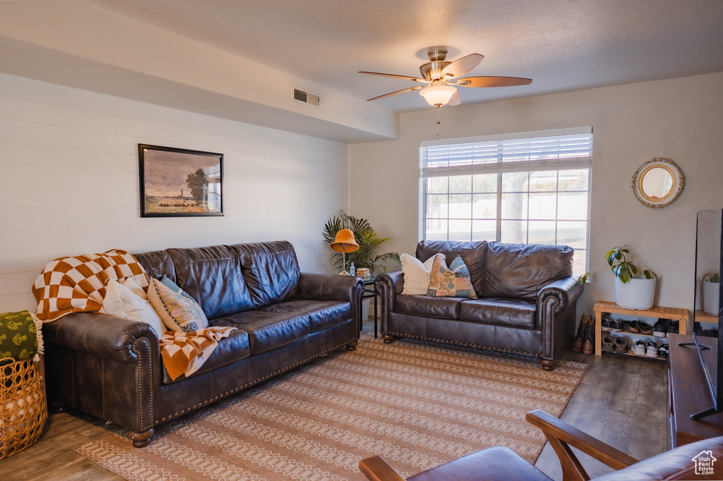 Living room with ceiling fan, wood finished floors, and visible vents