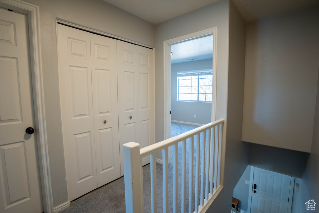 Hallway with carpet floors and an upstairs landing