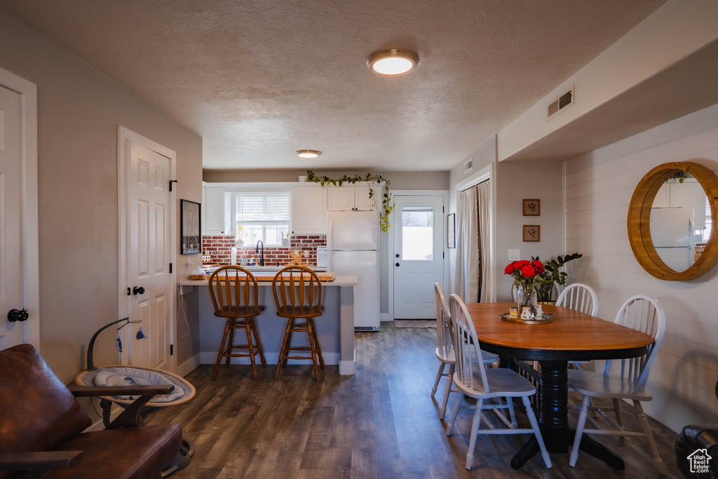 Dining area featuring a textured ceiling, visible vents, and dark wood-type flooring